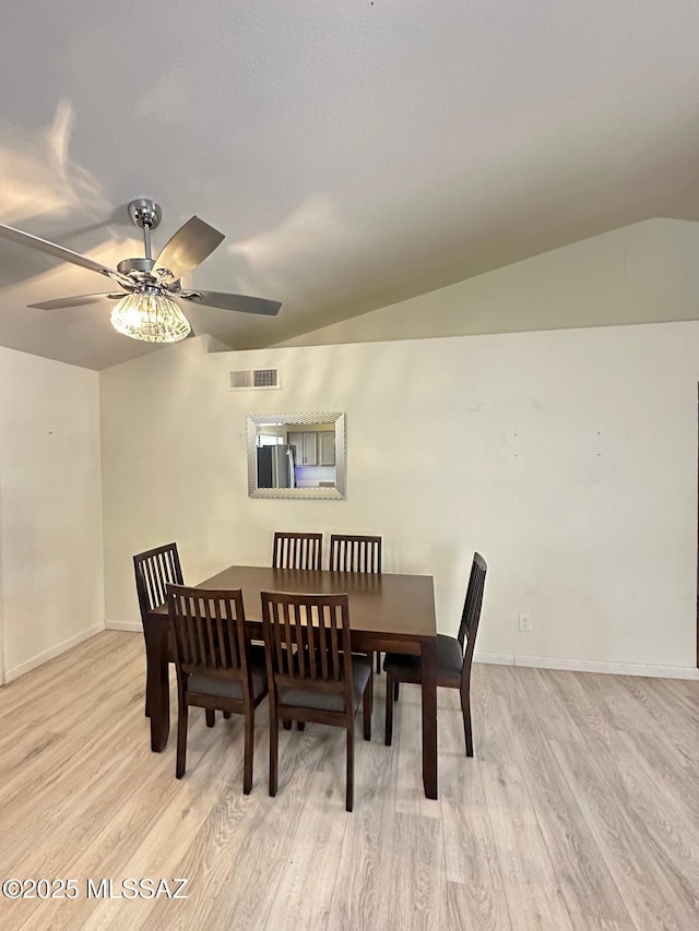 dining space with lofted ceiling, light wood finished floors, visible vents, and baseboards