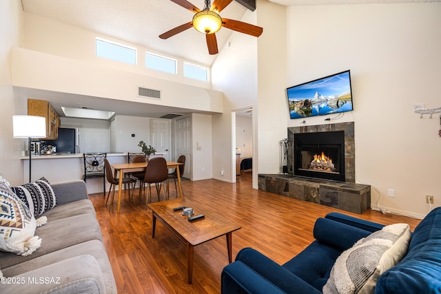 living area with visible vents, a tile fireplace, baseboards, and wood finished floors