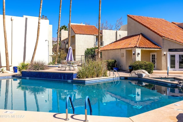 community pool with a patio, fence, and french doors