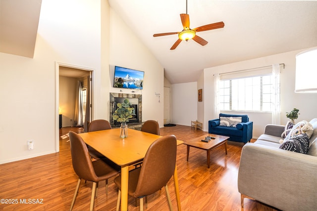 dining area with light wood-style flooring, baseboards, high vaulted ceiling, and ceiling fan