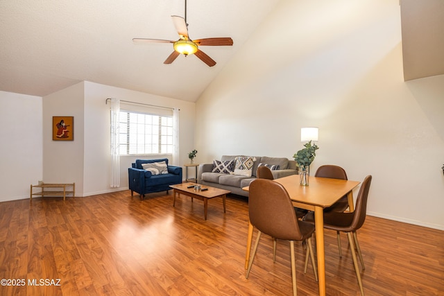 dining area featuring high vaulted ceiling, wood finished floors, baseboards, and ceiling fan