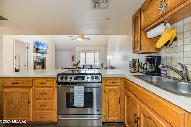 kitchen with visible vents, light countertops, a peninsula, electric range, and a sink