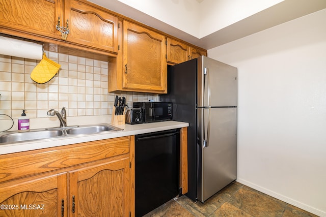 kitchen with stone tile flooring, a sink, black appliances, light countertops, and tasteful backsplash