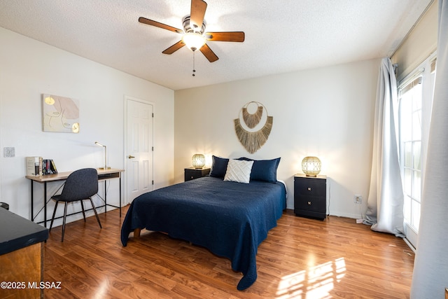 bedroom with a textured ceiling, a ceiling fan, and wood finished floors