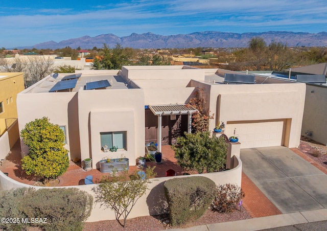 pueblo-style house with a garage, central AC, a mountain view, and stucco siding