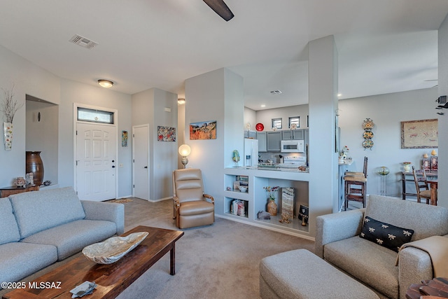 living area with visible vents, built in features, and light colored carpet