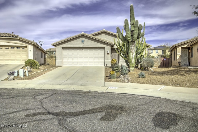 view of front of house featuring concrete driveway, a tile roof, an attached garage, and stucco siding