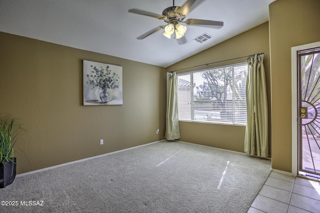 unfurnished room with light tile patterned floors, visible vents, a ceiling fan, light carpet, and vaulted ceiling