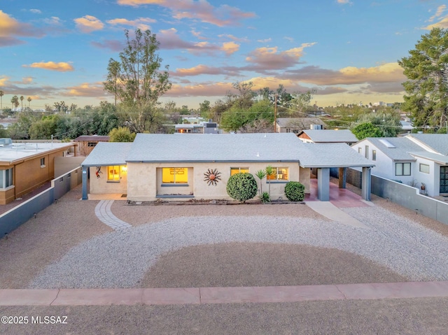 view of front of home featuring gravel driveway, fence, and stucco siding