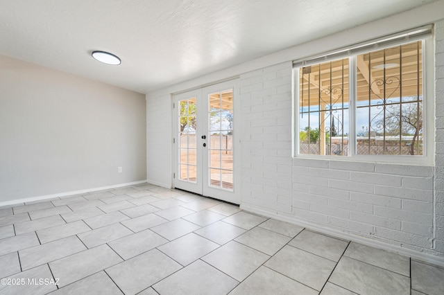 tiled empty room with french doors, plenty of natural light, and baseboards