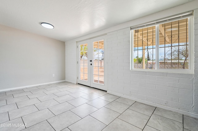 spare room with a wealth of natural light, baseboards, french doors, and tile patterned floors