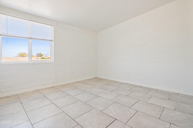 spare room with light tile patterned flooring and brick wall