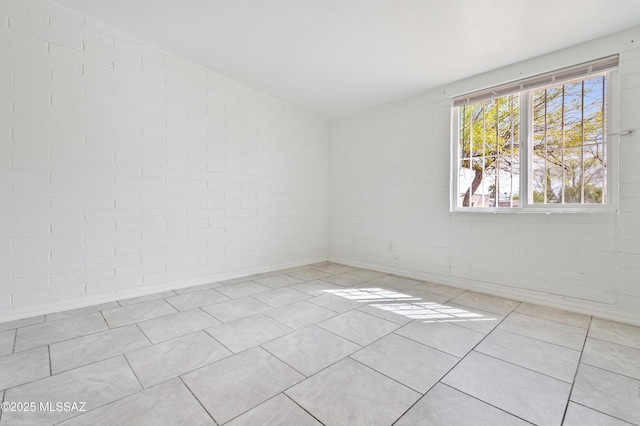 empty room featuring brick wall and tile patterned flooring