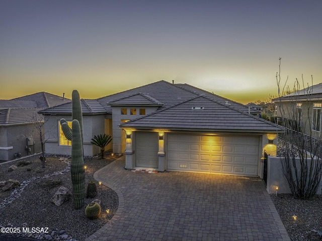 view of front of property with decorative driveway, a garage, and stucco siding