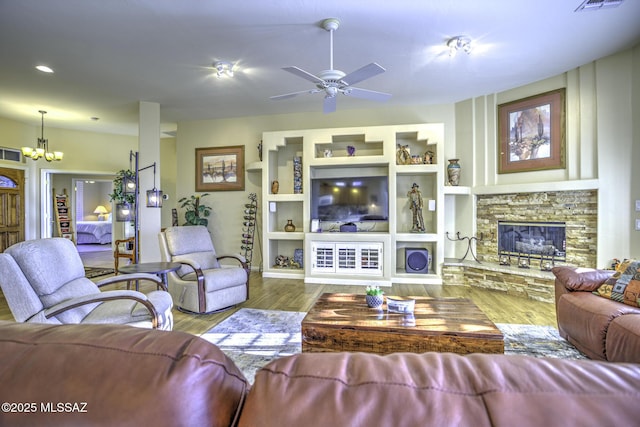 13517 N Heritage Gateway Ave, Marana, AZ 85658 - living area featuring built in shelves, wood finished floors, visible vents, a stone fireplace, and ceiling fan with notable chandelier