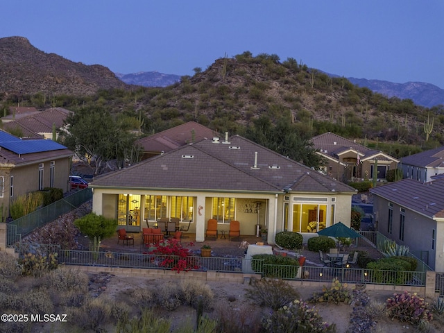 back of house with a fenced backyard, a mountain view, a tile roof, and a patio