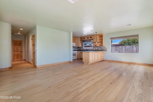 kitchen featuring white appliances, a sink, light wood-style floors, open floor plan, and dark countertops