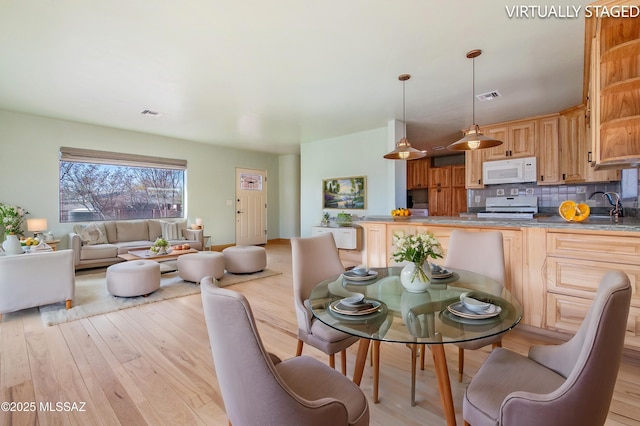 dining area featuring light wood-style floors and visible vents