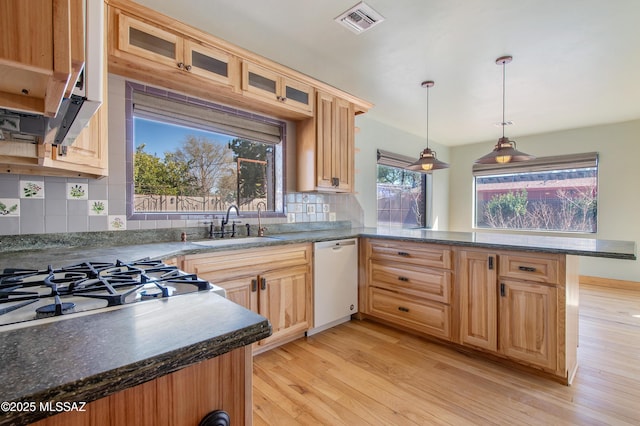 kitchen featuring visible vents, glass insert cabinets, a peninsula, white dishwasher, and light wood-style floors