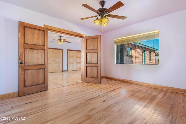 empty room featuring light wood-type flooring, a ceiling fan, and baseboards