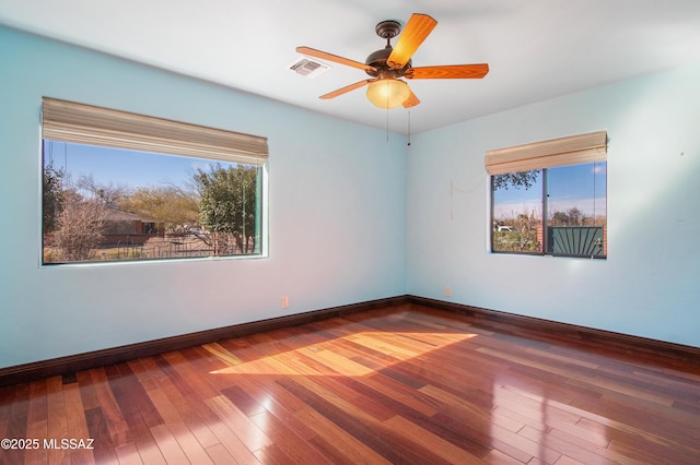 empty room featuring a healthy amount of sunlight, visible vents, and wood-type flooring