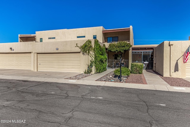 adobe home featuring a garage, driveway, fence, and stucco siding