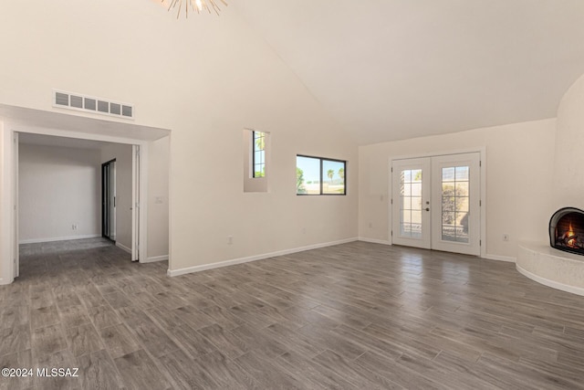 unfurnished living room featuring a large fireplace, visible vents, wood finished floors, and french doors