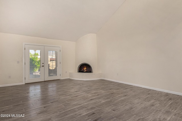 unfurnished living room with a large fireplace, baseboards, lofted ceiling, dark wood-style flooring, and french doors