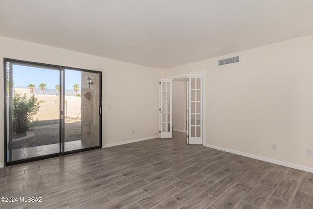 spare room with dark wood-style floors, french doors, visible vents, and baseboards