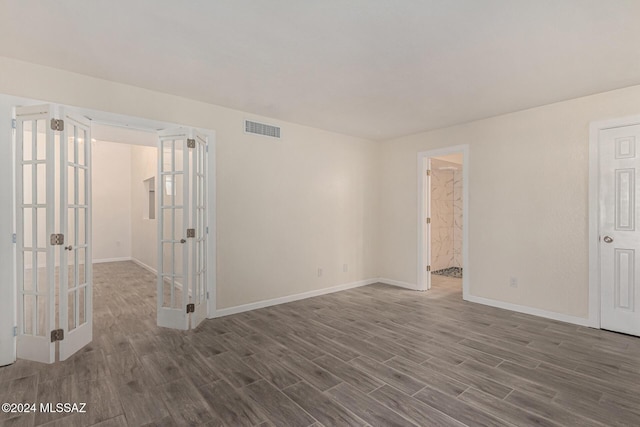 spare room featuring french doors, visible vents, baseboards, and wood finished floors