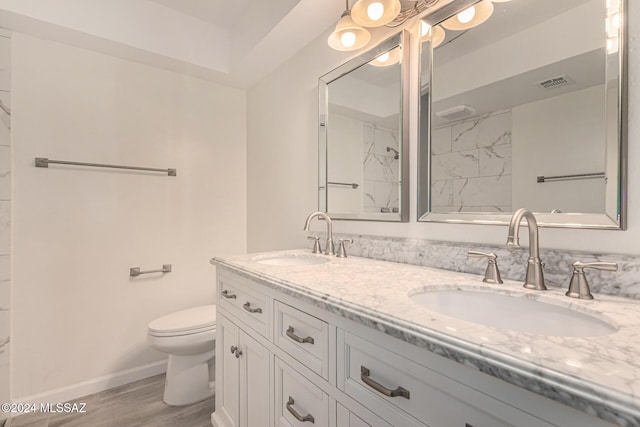 full bathroom featuring toilet, double vanity, visible vents, and a sink