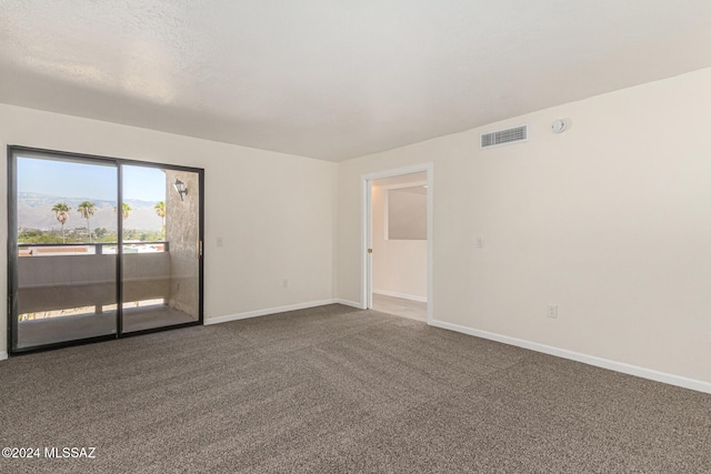 unfurnished room with visible vents, dark carpet, and baseboards