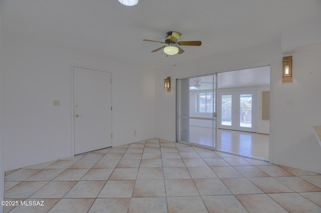 empty room featuring light tile patterned floors, ceiling fan, and french doors