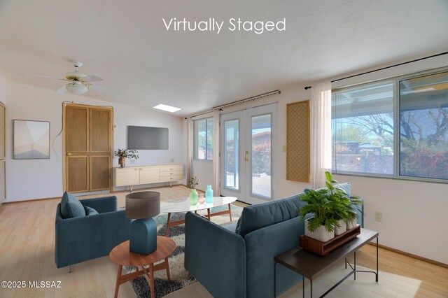 living room with lofted ceiling, light wood finished floors, baseboards, and french doors