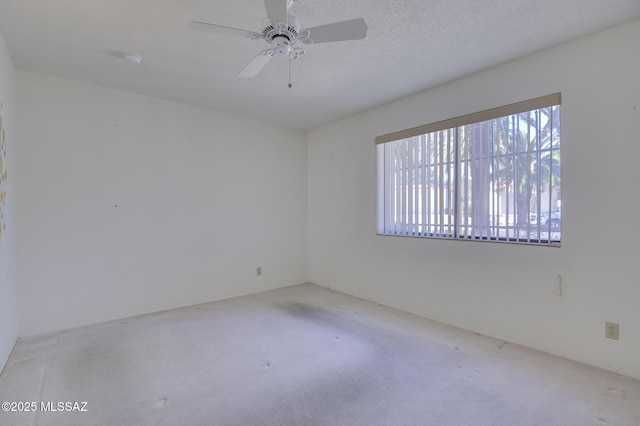 carpeted spare room with a textured ceiling and a ceiling fan