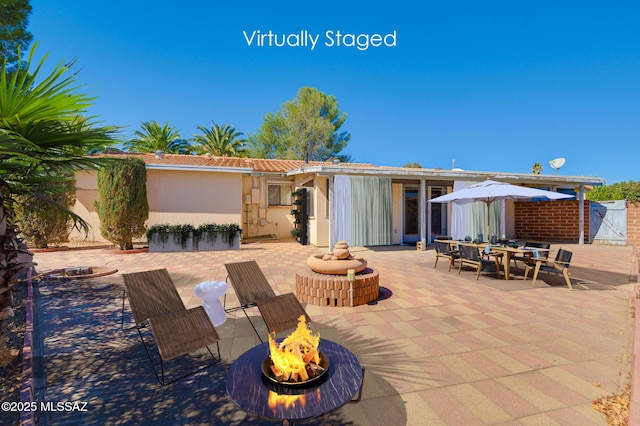 back of property featuring a tile roof, a patio area, and a fire pit