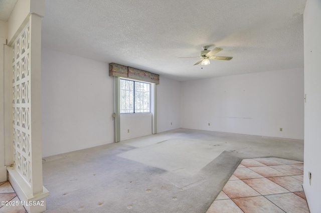 carpeted empty room featuring ceiling fan and a textured ceiling