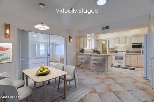 dining space featuring light tile patterned floors, visible vents, and a textured ceiling