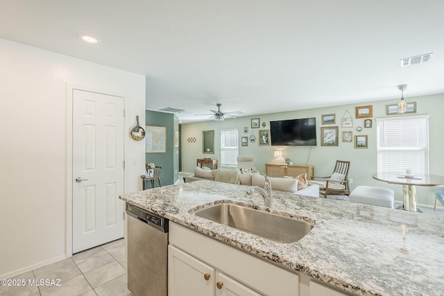 kitchen with visible vents, white cabinets, stainless steel dishwasher, a sink, and light tile patterned flooring