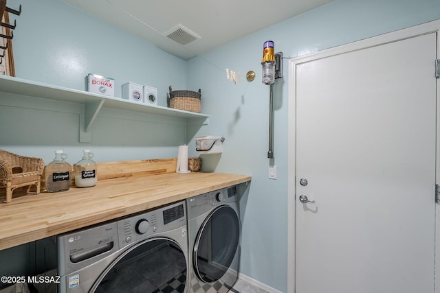 laundry area with laundry area, washing machine and dryer, and visible vents