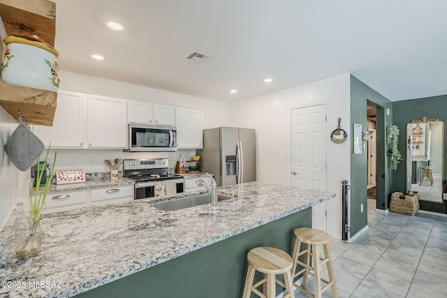 kitchen featuring light stone counters, appliances with stainless steel finishes, a sink, and visible vents