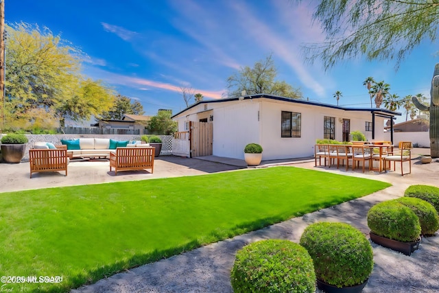 rear view of house with a yard, a patio, an outdoor living space, and fence