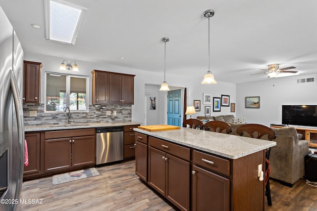 kitchen featuring visible vents, a breakfast bar area, open floor plan, stainless steel appliances, and a sink