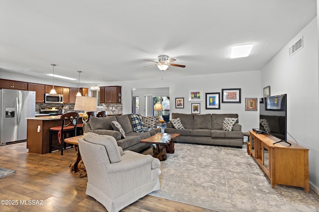 living room featuring ceiling fan, visible vents, and wood finished floors