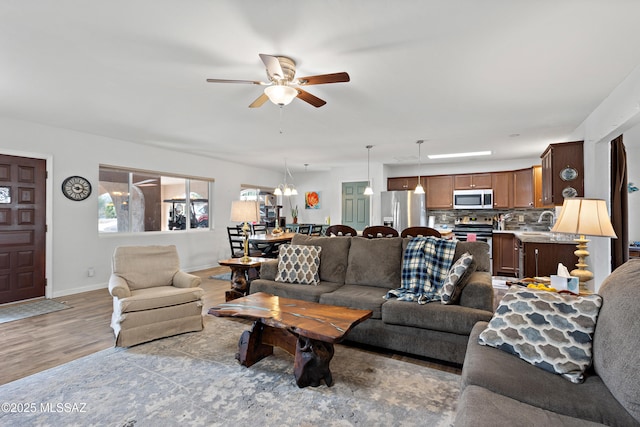 living area featuring ceiling fan, baseboards, and wood finished floors