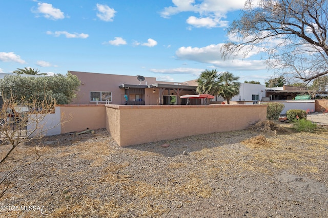 rear view of property featuring a fenced front yard and stucco siding