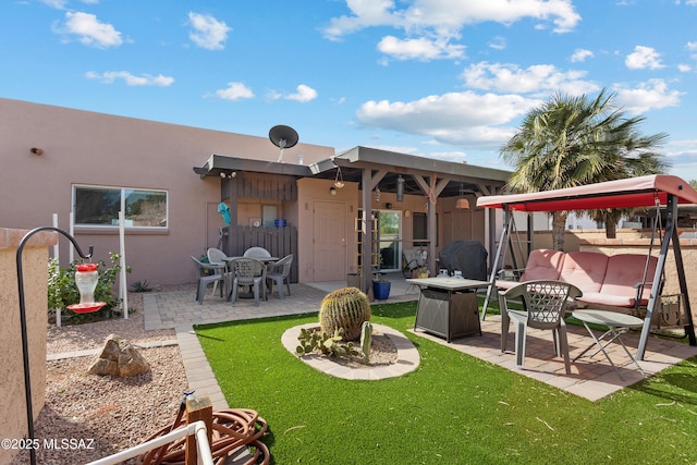 rear view of house featuring a patio area, a lawn, and stucco siding