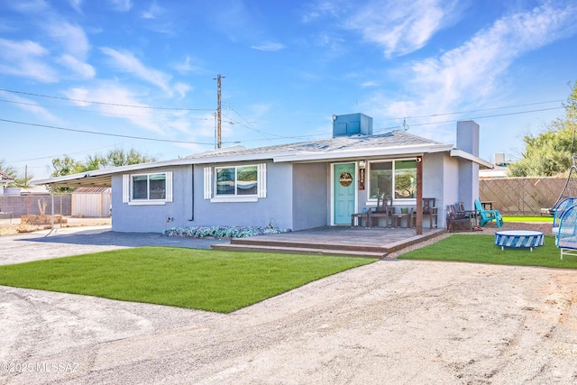 ranch-style home featuring an attached carport, fence, driveway, stucco siding, and a front yard