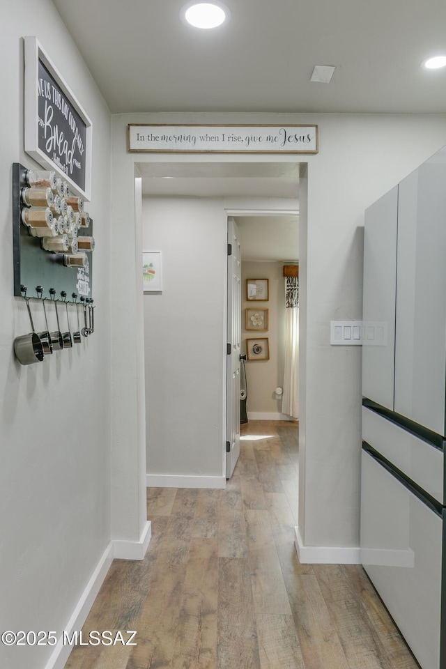 hallway with light wood-type flooring and baseboards