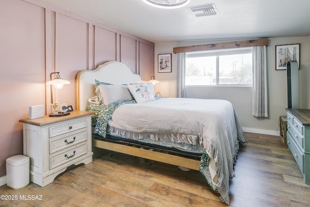 bedroom with light wood-style flooring, visible vents, and baseboards